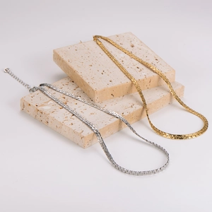 Minimalist snake chain necklaces in gold and silver finish on textured beige stones