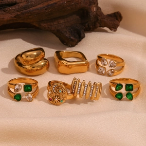 Close-up of vintage 18K gold plated ring set with emerald and zircon on beige silk cloth
