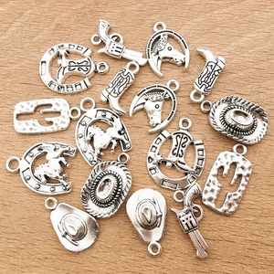 Flat lay of vintage silver western charms featuring cowboy hats and boots on wood background