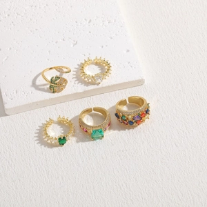 Detailed view of luxury gold-plated rings set with colorful zircon on stone background