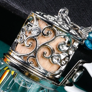 Macro shot of silver hollow pattern car diffuser with teal crystal and wood core