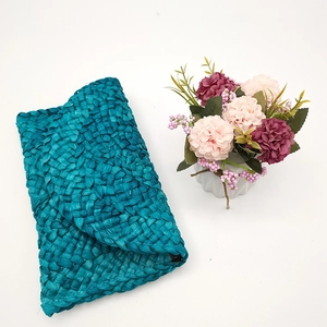 Vista dettagliata della pochette a busta in paglia intrecciata blu pavone con fiori