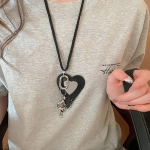 Close-up of leather heart pendant with silver elephant charm on a long black necklace