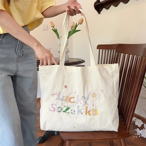 Détail de la broderie Lucky Sozakka colorée sur un sac cabas en toile blanc crème