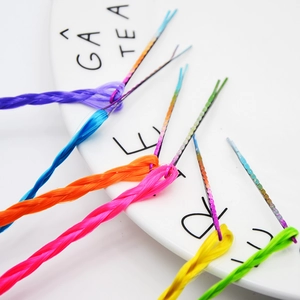 Close-up of six colorful braided hair extensions with metal clips on a white plate