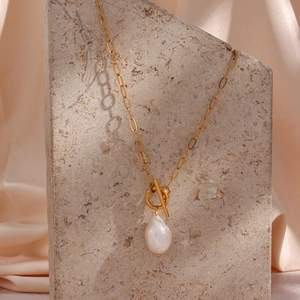 Close-up of baroque pearl pendant on golden paperclip chain necklace with OT clasp