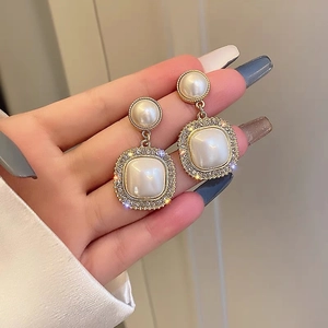 Elegant C-shaped gold pearl earrings with zircon stones shown on a model for display