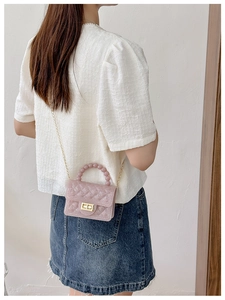 Pink PVC jelly bag with pearl handle and gold chain strap worn as a crossbody