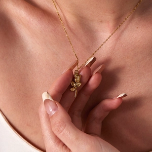 Detailed view of an 18K gold plated 3D rose flower pendant necklace on skin