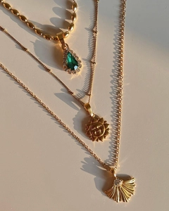 Détail de colliers plaqués or 18k avec pendentifs soleil et coquillage et pierre verte