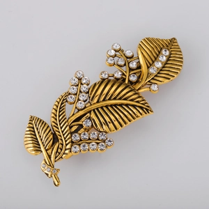Macro detail of vintage gold leaf hair clip with intricate veins and white rhinestones