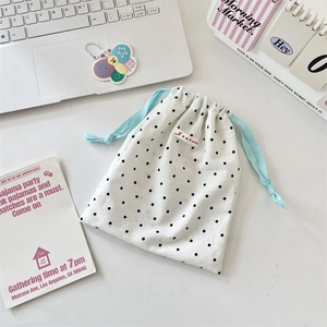 Close-up of white polka dot drawstring storage bag set with a minimalist lifestyle decor