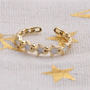 Detail of adjustable gold star chain ring featuring white enamel star accents
