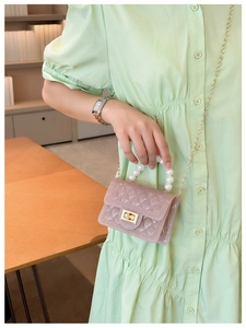 Detailed view of pink jelly bag with pearl handle and quilted texture on green dress