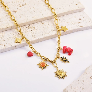 Golden titanium steel necklace with sun, star and red heart charms on marble stone