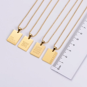 Detail view of rectangular gold engraved pendants with motivational quotes and bead chains