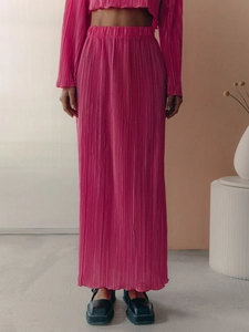 Detail of fuchsia pleated two-piece set featuring flared sleeves and long skirt