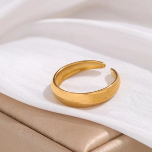 Detail of adjustable 18K gold plated stainless steel open ring on white satin fabric