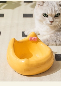 Close-up of yellow ceramic cat bowl featuring a 3D pink bow and smooth glaze finish