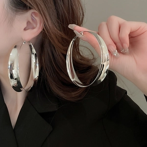 Chic oversized silver geometric hoop earrings worn by a model in a minimalist style