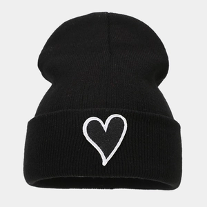 Close-up of black knitted beanie featuring white heart patch embroidery on the cuff