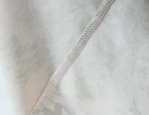 Détail macro de la couture intérieure sur le tissu satiné à imprimé doré de la robe