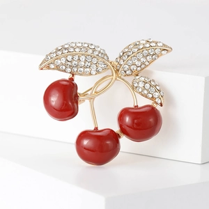 Detail of a golden cherry brooch featuring red enamel fruits and sparkling rhinestones