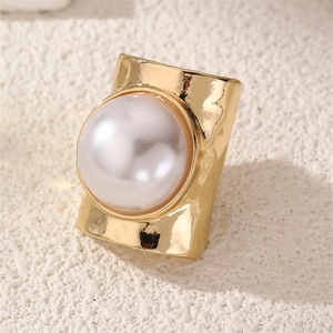 Detailed close-up of a wide hammered gold ring featuring a large centered white pearl inlay