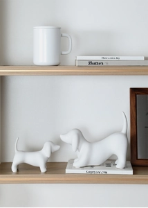 Close-up of modern ceramic dachshund figurines on a wooden shelf in a minimalist home setup