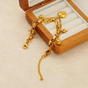 Détail du bracelet multicouche doré avec cœur posé sur un écrin à bijoux en bois chic