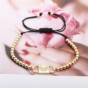 Adjustable black rope bracelet with gold copper beads and zircon moon charm on floral backdrop