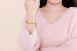 Detail of a minimalist gold hollow bead titanium steel bracelet worn by a model