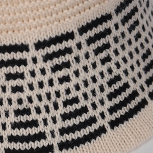 Close-up of knit fabric with black and beige geometric diamond pattern jacquard texture
