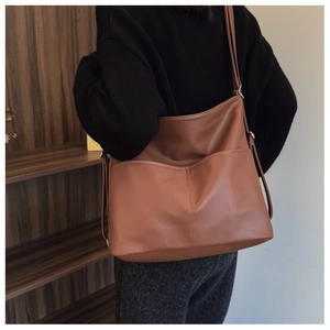 Detailed close-up of brown pebbled leather tote bag featuring two front open pockets