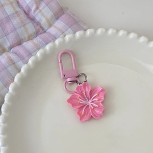 Detailansicht eines rosa Kirschblüten-Schlüsselanhängers aus Harz auf weißem Teller