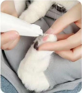 Close-up of a white pet hair trimmer being used to trim fur between a cat's paw pads