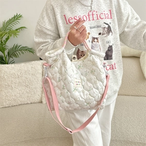 Détail du sac à main matelassé blanc avec motifs de lapins à fleurs et sangle rose