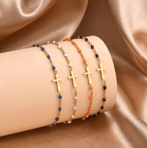 Colorful beaded cross bracelets in blue white orange and black on gold silk display