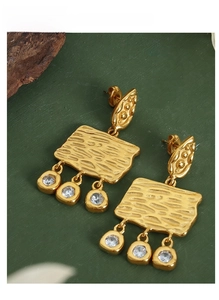 Close-up of vintage gold earrings with textured plates and sparkling zircon tassels