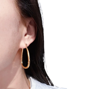 Close-up detail of a glossy 24k gold plated geometric square hoop earring on model ear