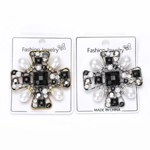 Close-up of Baroque cross brooches with black gemstones, pearls and crystals in gold and silver