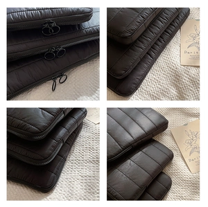 Detail view of black quilted laptop sleeve with dual zippers and padded stripe texture