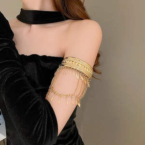 Détail des pendentifs feuilles dorées et des chaînes multicouches du bracelet de bras
