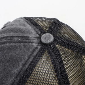 Detail of grey washed cotton top button and breathable mesh on a vintage trucker hat