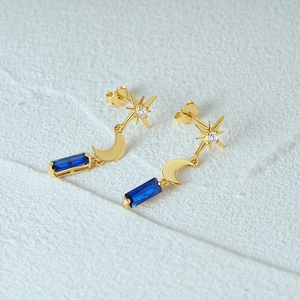 Macro detail of gold S925 star moon earrings with elegant blue rectangle gemstones