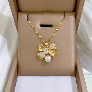 Luxurious gold titanium necklace with sparkling diamond bow and pearl in a jewelry box