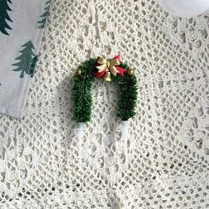 Détail d'un pic à gâteau en couronne de Noël verte avec des nœuds rouges et dorés décoratifs