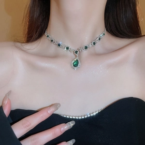 Detail of emerald green teardrop pendant necklace worn by model showing shiny rhinestones