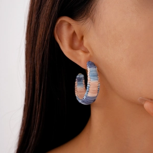 Detail of C-shaped hoop earring featuring pink and blue gradient woven raffia texture