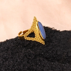 Detail view of a vintage gold ring with an oval blue gemstone on a textured black surface